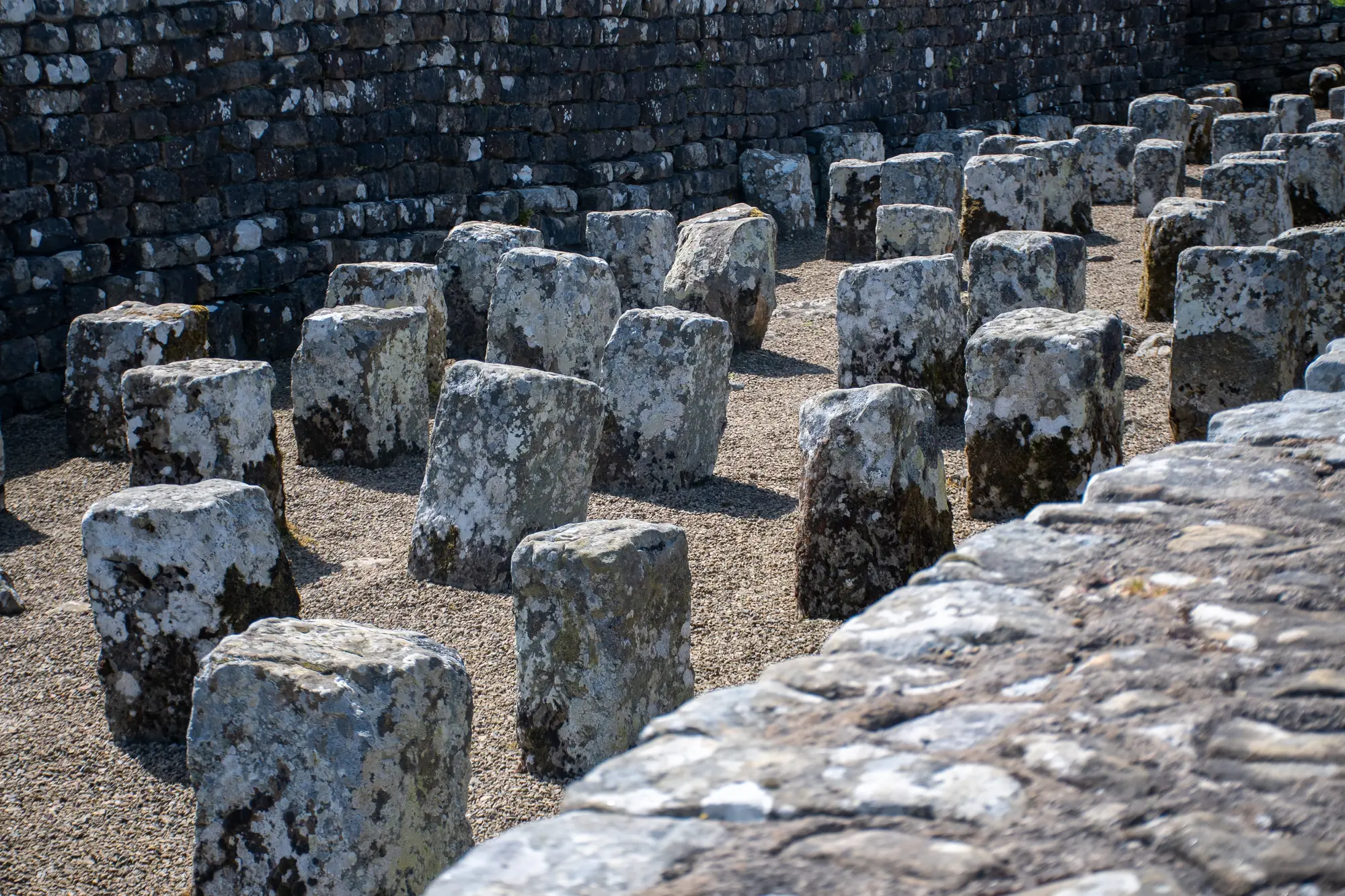 Stones from Hadrian's Wall standing on the ground next to the wall